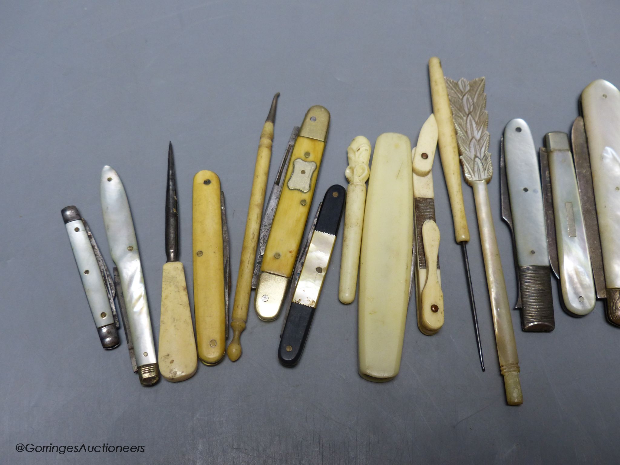 A group of silver and steel bladed pocket folding knives and a fork